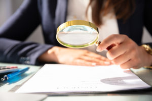 Businesswoman Looking At Contract Form Through Magnifying Glass