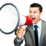 Shot of an asian businessman shouting into a megaphone against a studio background