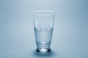 Half full water glass over blue background