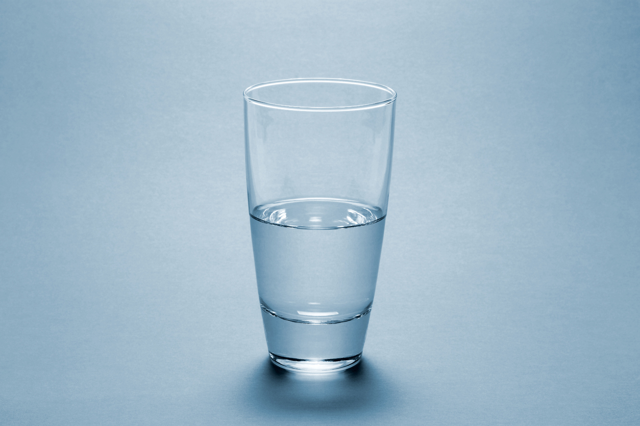 Half full water glass over blue background