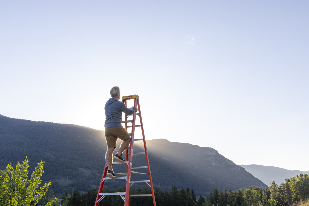 Senior man climbs ladder