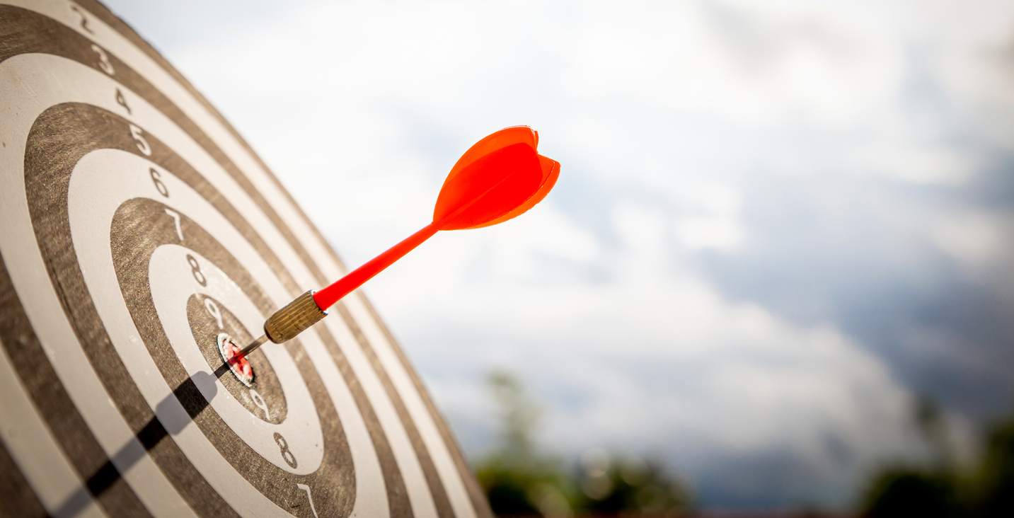 Close up shot red darts arrows in the target of dartboard center on dark blue sky background. Business target or goal success and winner concept.