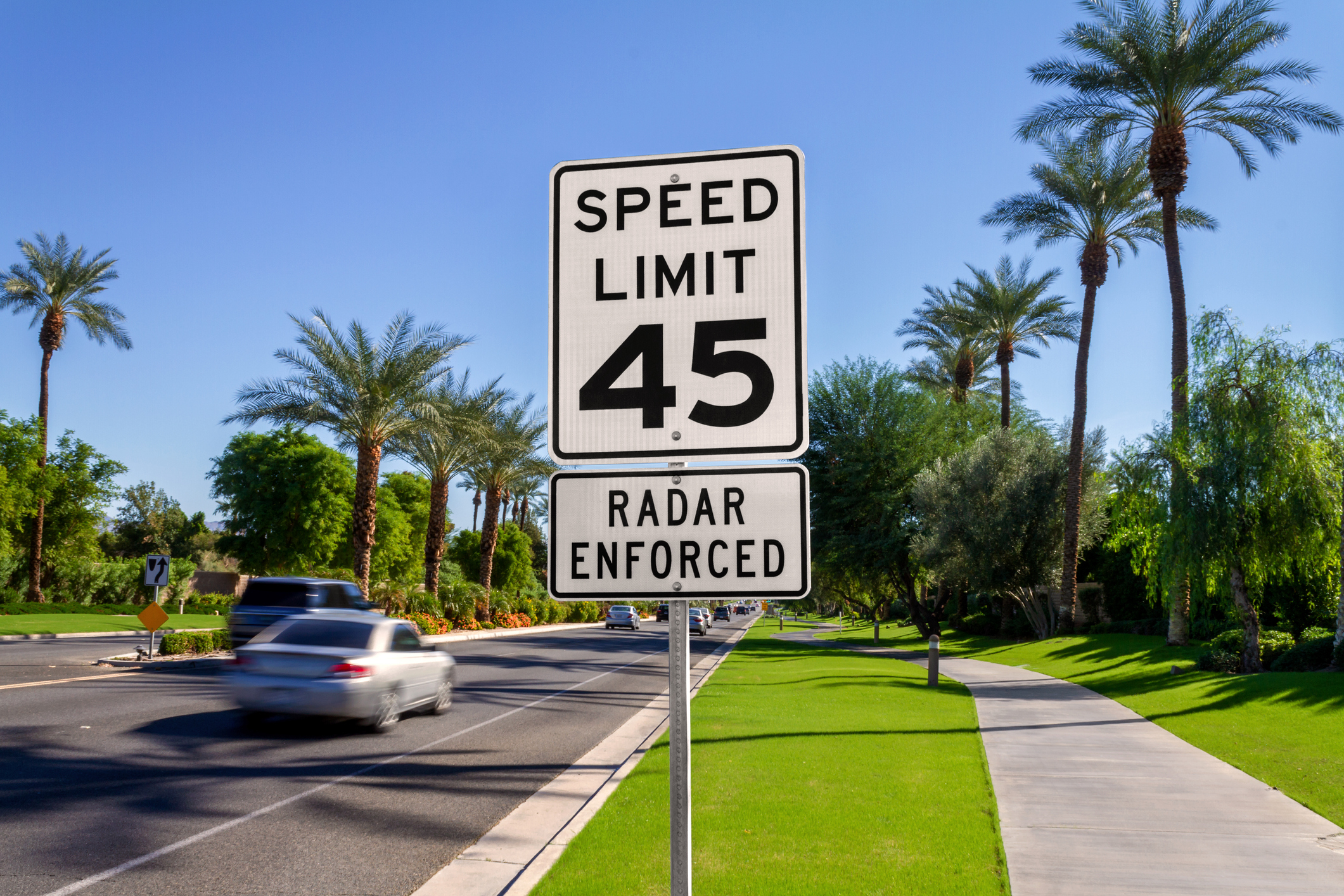 Speed Limit 45 Radar Enforced road sign with passing cars on a California street.