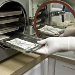 Technician Inserts Surgical Instruments in Autoclave for Sterilization.