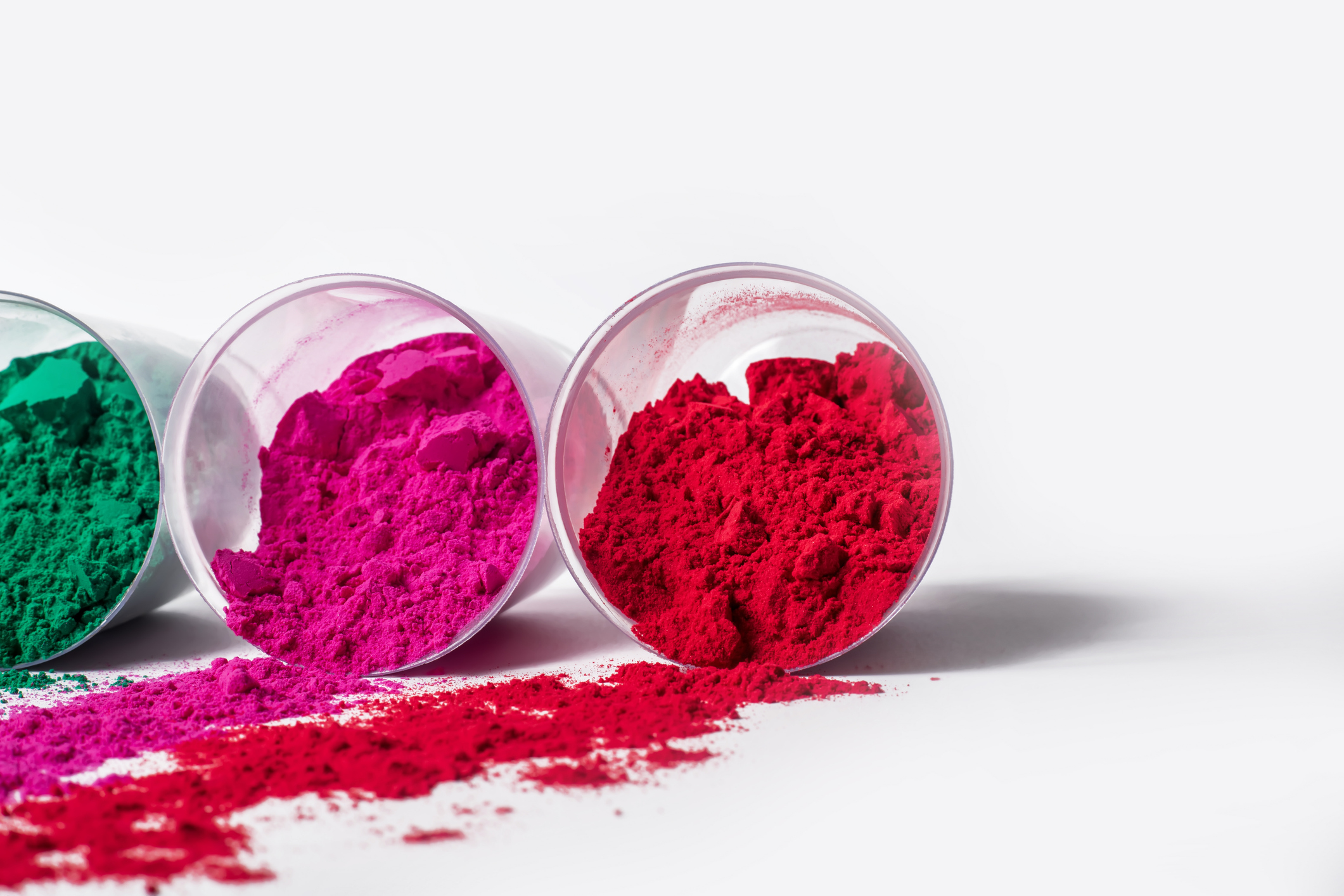 Colorful holi powder in a plastic containers on white background.